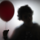 Foggy silhouette of creepy person holding a red balloon